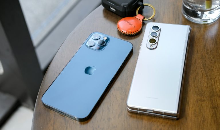 two cell phones sitting on top of a wooden table
